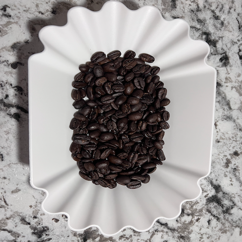BOLDLY GO Medium Dark Blend coffee beans in a white scalloped container on a marbled surface.