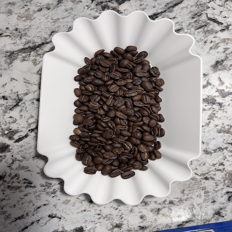 Medium blend coffee beans in a white fluted tray on a marble surface.